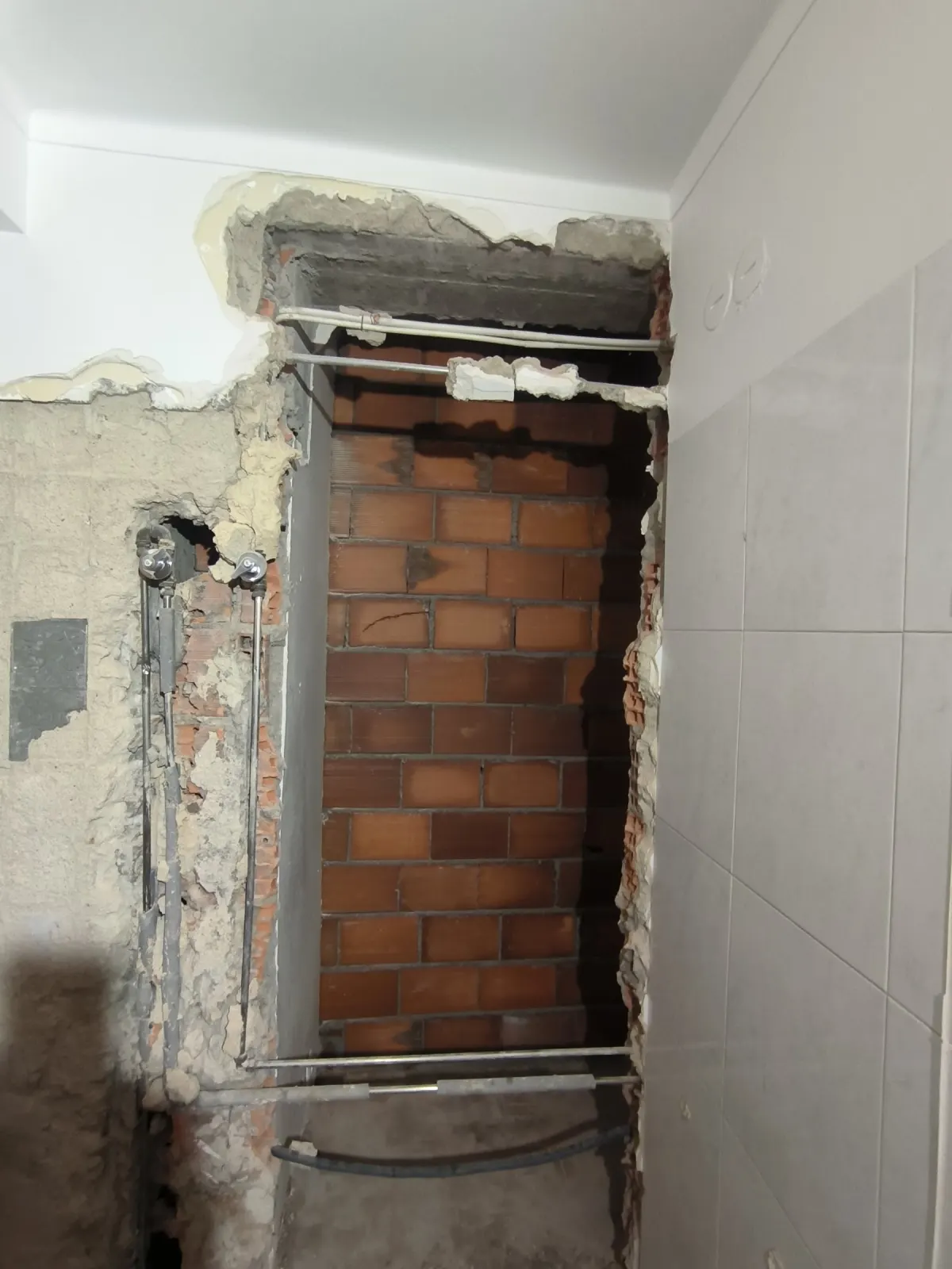 Vão fechado com tijolo junto a parede azulejada