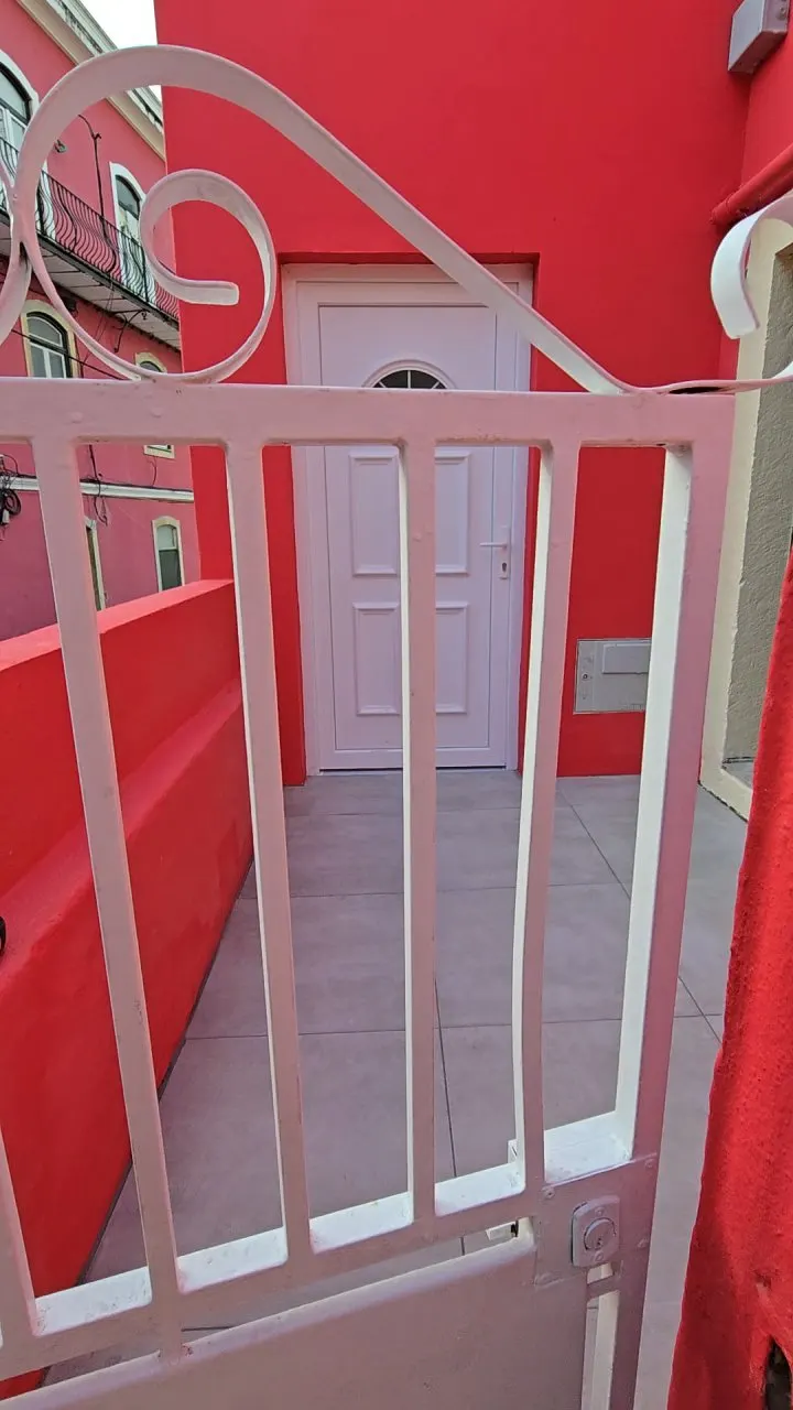 Portão branco e pátio renovado da moradia, com a porta de entrada nova