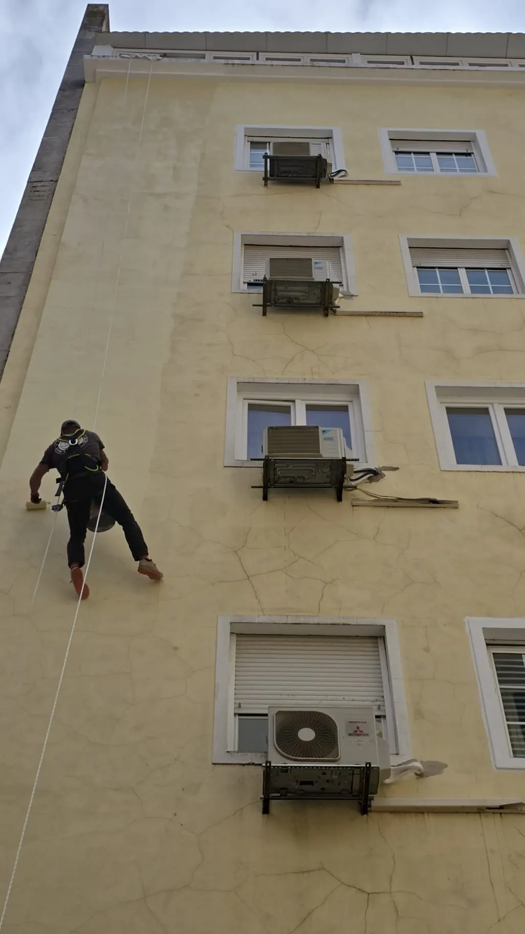 Trabalho vertical de reparação de fachada com acesso por corda