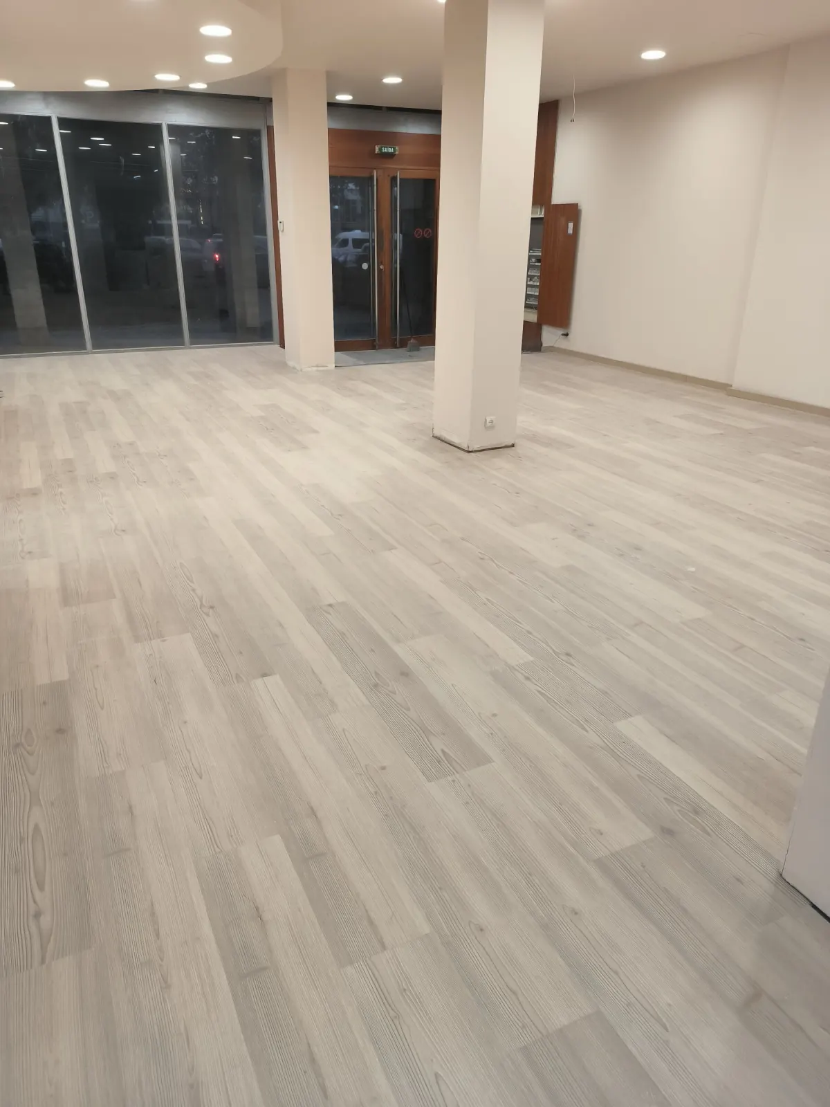 Loja com pavimento flutuante claro, pilares e montra envidraçada